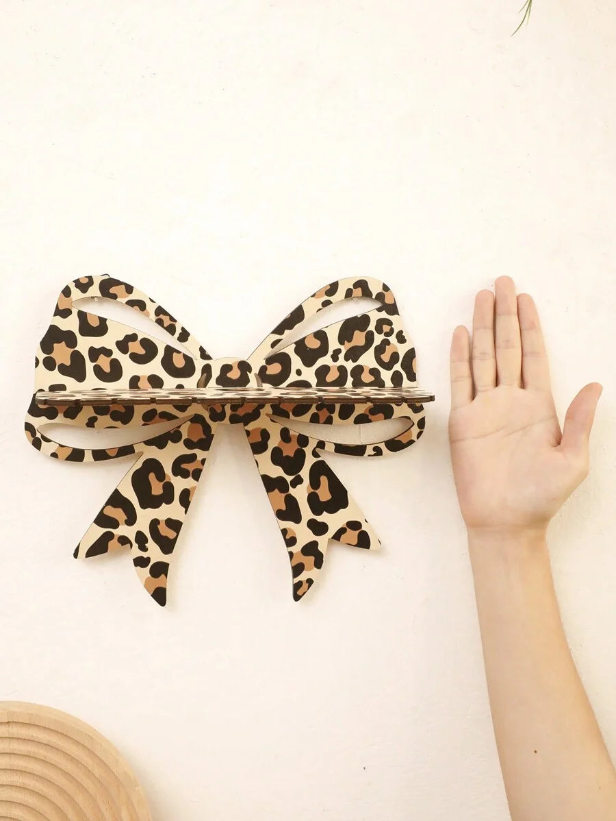 A leopard print bow-shaped wall mounted storage rack is displayed against a white background.