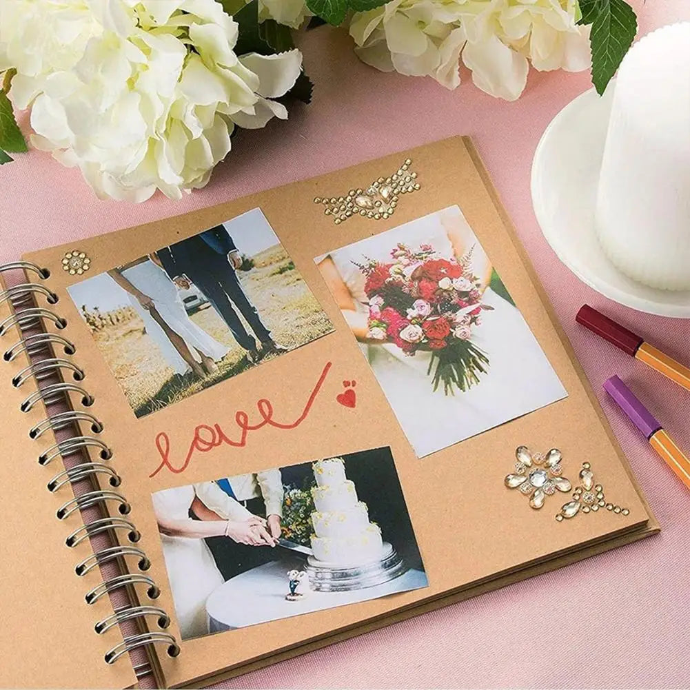 A DIY hardcover scrapbook album with gold embellishments and photos, surrounded by white flowers.