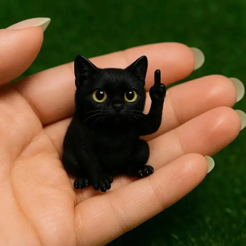 A small black kitten with bright yellow eyes is held in a person's hand against a green background.