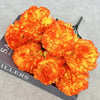 A bouquet of vibrant orange and yellow silk artificial chrysanthemum flowers displayed on a dark surface.