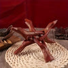 A vintage wooden tripod stand for displaying an abalone shell and crystal ball on a woven mat.