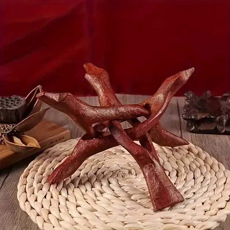 A vintage wooden tripod stand for displaying an abalone shell and crystal ball on a woven mat.