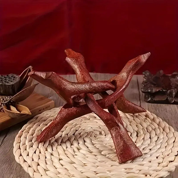 A vintage wooden tripod stand for displaying an abalone shell and crystal ball on a woven mat.