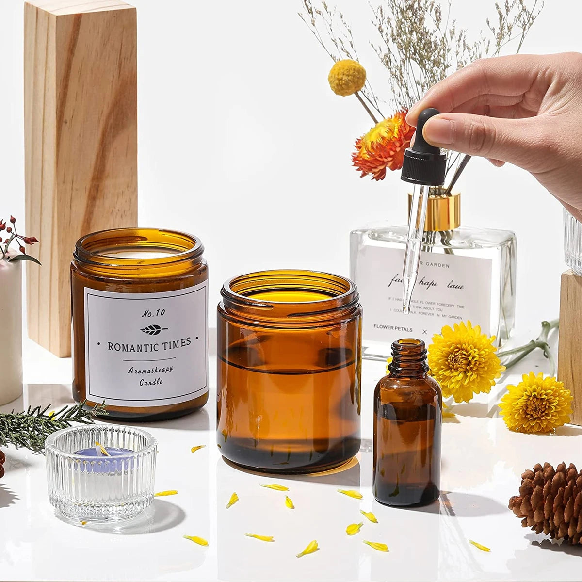 Two amber glass jars with airtight lids and labels sit next to a hand holding dried flowers.