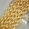 A close-up of a long string curtain made of small, light yellow or beige beads and tassels.