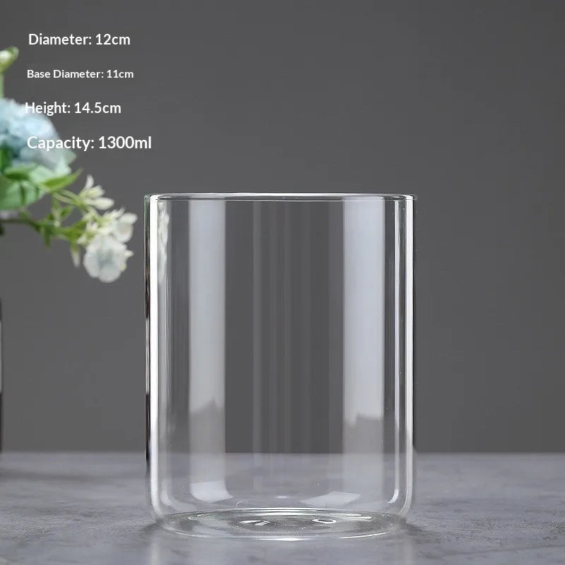 A clear glass cylindrical vase with a wide opening, shown against a gray background.