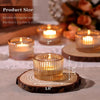 Gold glass tealight candle holders resting on a wooden slice with a lit candle.
