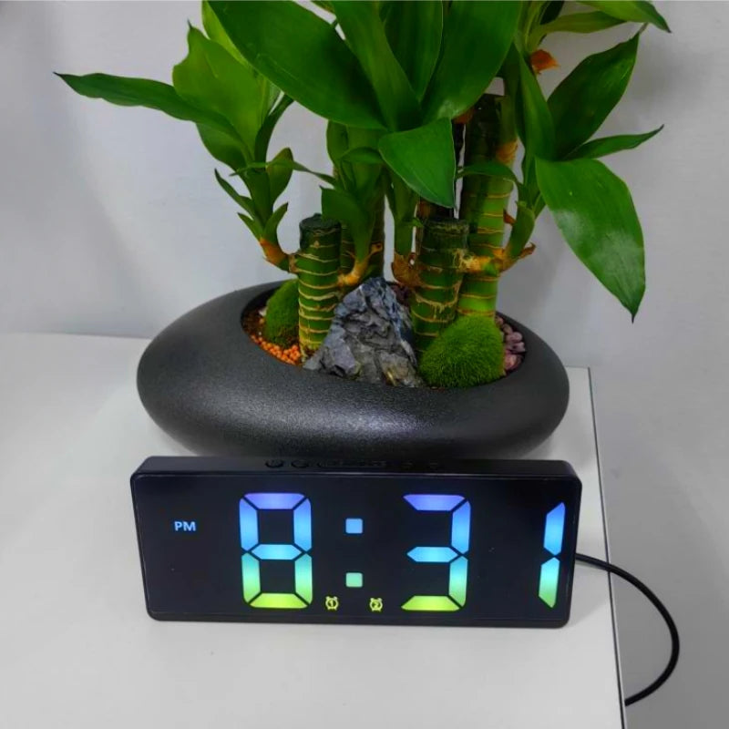 A voice-activated digital alarm clock displaying 8:31, sitting in front of a potted plant.