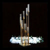 A vertical arrangement of elegant gold metal candle holders with clear glass tubes, set against a dark background and surroun