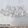 A silver foil letter birthday balloon set spelling out HAPPY BIRTHDAY hanging on a white wall.