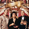 Three men pose in front of a large golden globe sculpture with the text The World Is Yours