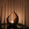 A wooden lotus candle holder with multiple slender candles casting shadows on a wall.