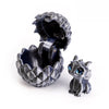 A dark gray dragon egg is cracked open, revealing a small, detailed miniature dragon toy inside.