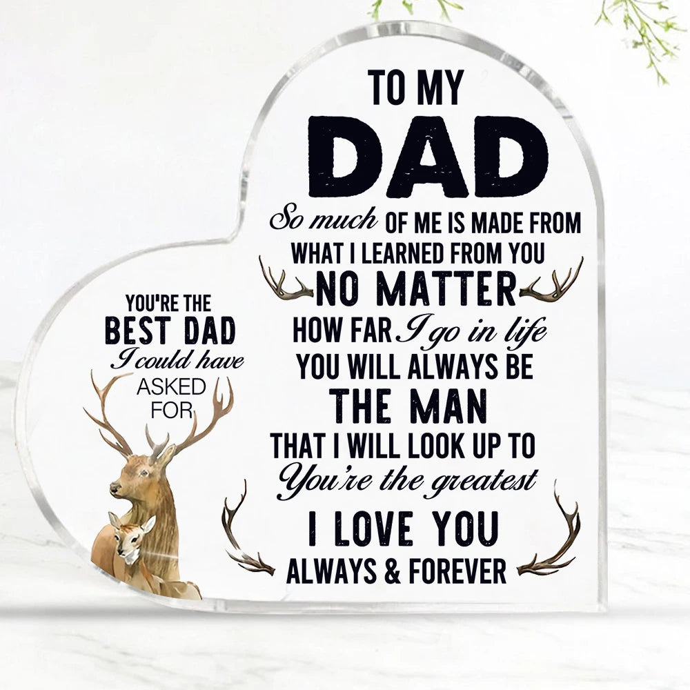 A clear heart-shaped glass sign with black text dedicated to a dad, featuring deer antlers and loving messages.