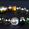 A bracelet made of polished crystal beads, featuring gold and colored stones, laid on a dark surface.