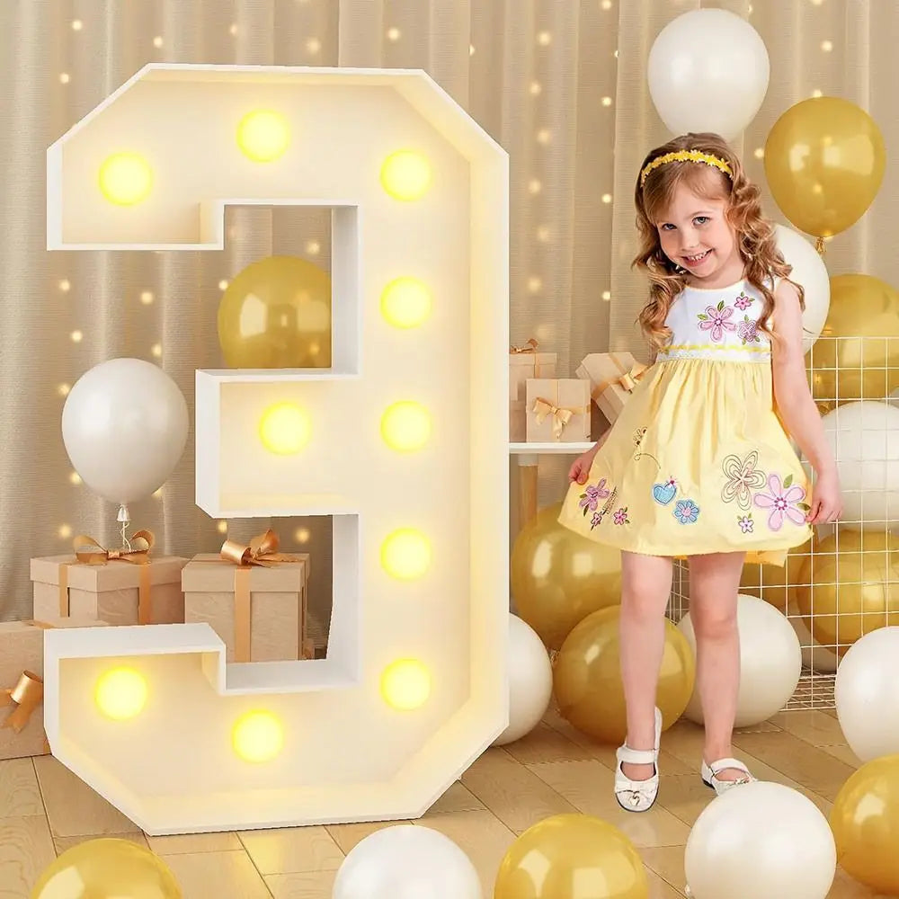 A large, illuminated letter E balloon decoration surrounded by yellow and white balloons for a party.