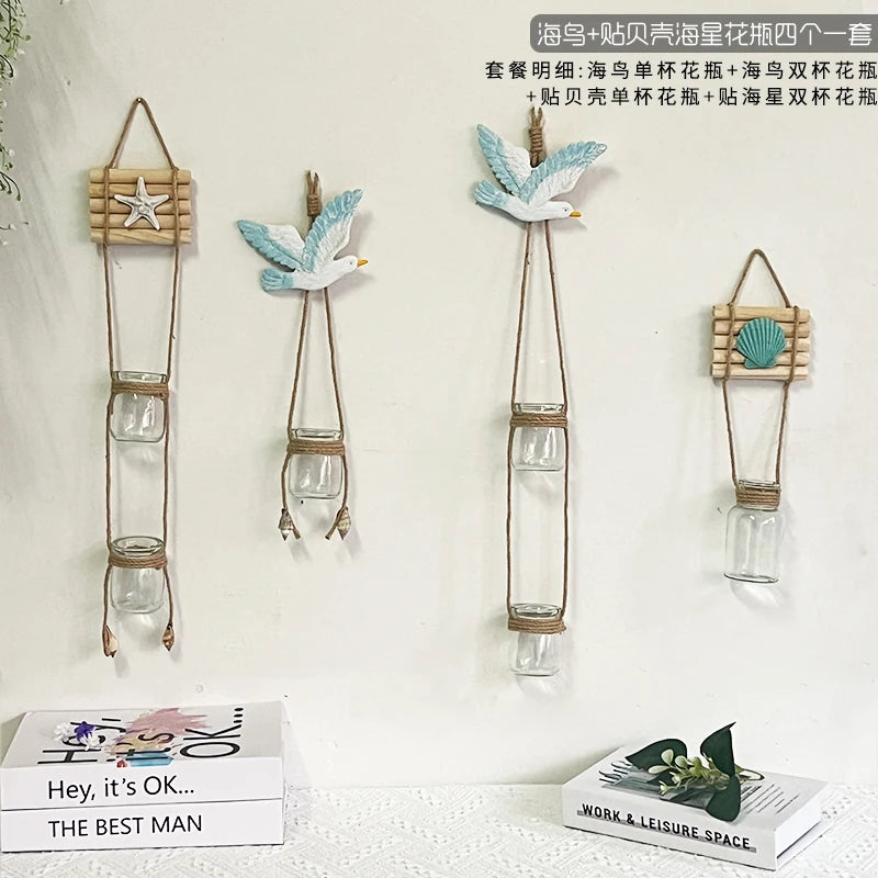 Three decorative glass terrariums with bird-shaped elements hanging on a white wall