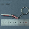 A miniature replica of an alloy gun is attached to a silver keyring, measured against a ruler.