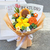 A bouquet of handmade crochet flowers in yellow, orange, and white arranged in a paper wrapping.