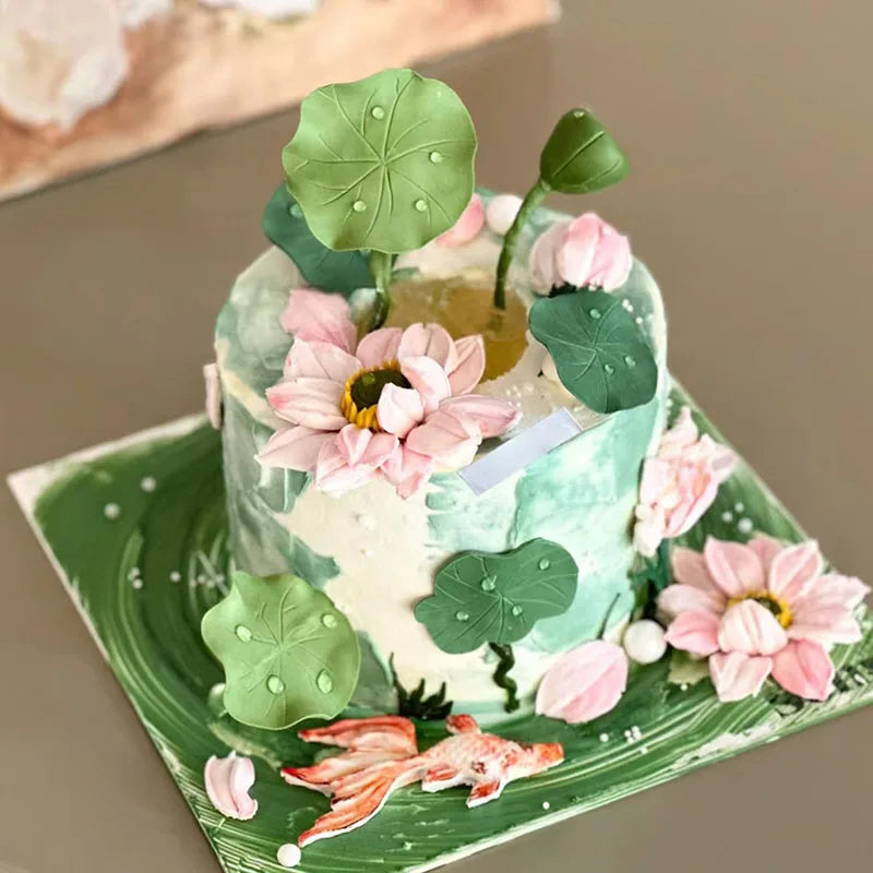 A cake decorated with green and pink floral elements and leaves on a light green platter.