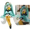 A PVC collectible figurine of Hatsune Miku in a school uniform with teal hair and yellow accents.