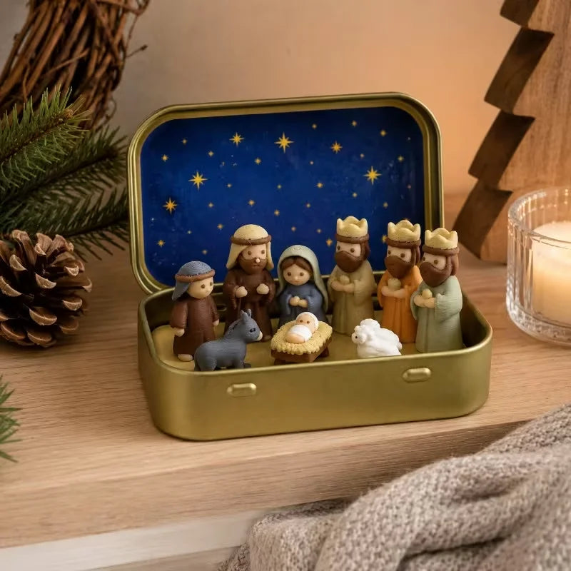 A gold-colored metal box containing a miniature nativity scene with figures and a blue starry background.