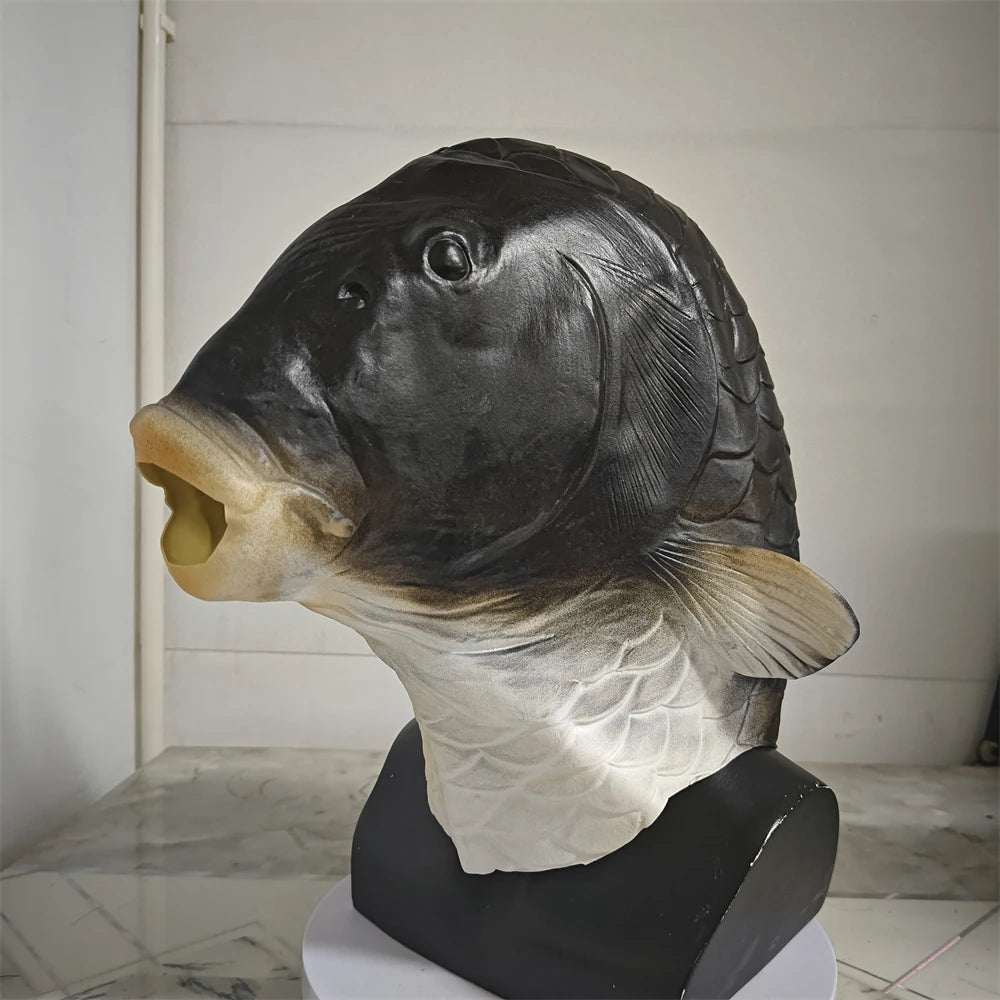 A realistic latex mask of a fish head with a large mouth and fins, displayed on a black stand.