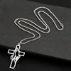 Silver hollow prayer hands cross pendant necklace displayed on a black surface.