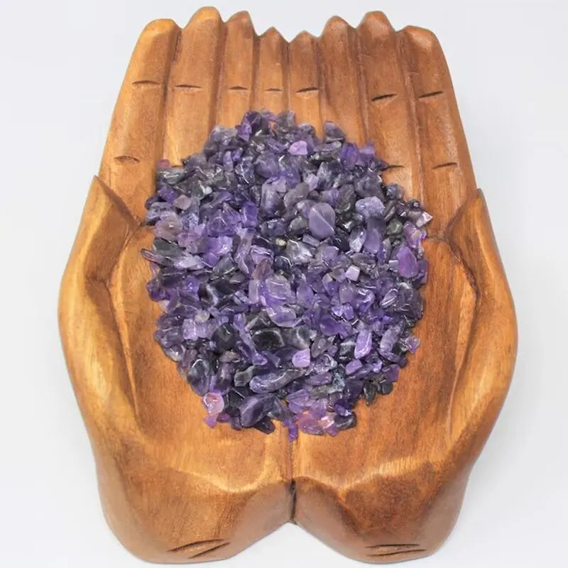 A pile of purple tumbled gemstone chips in a wooden dish for crafts and jewelry making
