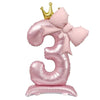 A foil balloon shaped like the number 3 in pink with a gold crown topper