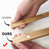 A hand holds a natural teak wood magnetic poster frame, demonstrating its use for wall art display.