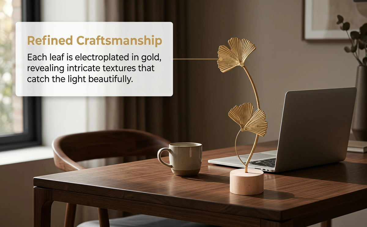 Gold electroplated ginkgo leaf ornament set displayed on a wooden table next to a laptop and a cup.