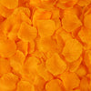 A close-up of bright orange artificial silk rose petals scattered across a surface.
