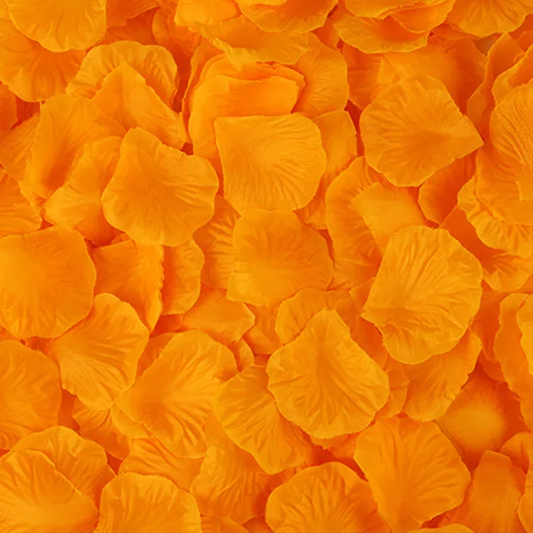 A close-up of bright orange artificial silk rose petals scattered across a surface.
