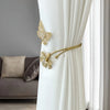 Gold decorative flower butterfly curtain tiebacks attached to a white sheer curtain.