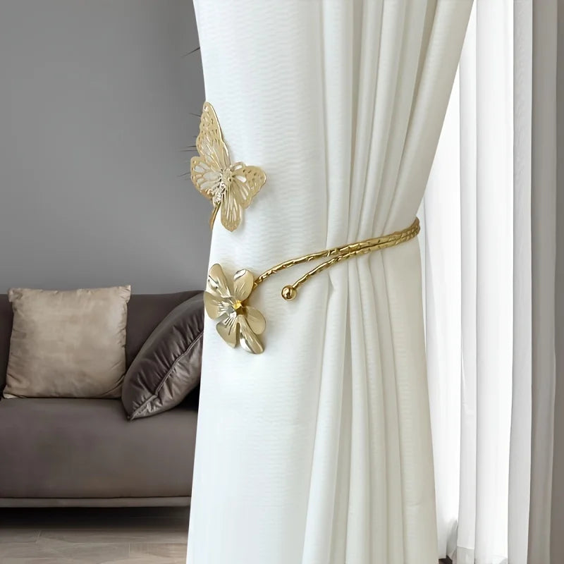 Gold decorative flower butterfly curtain tiebacks attached to a white sheer curtain.