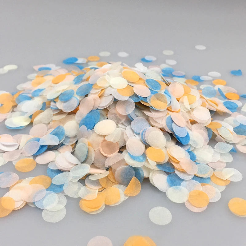 A pile of multicolor paper confetti consisting of light blue, peach, and yellow circular pieces.