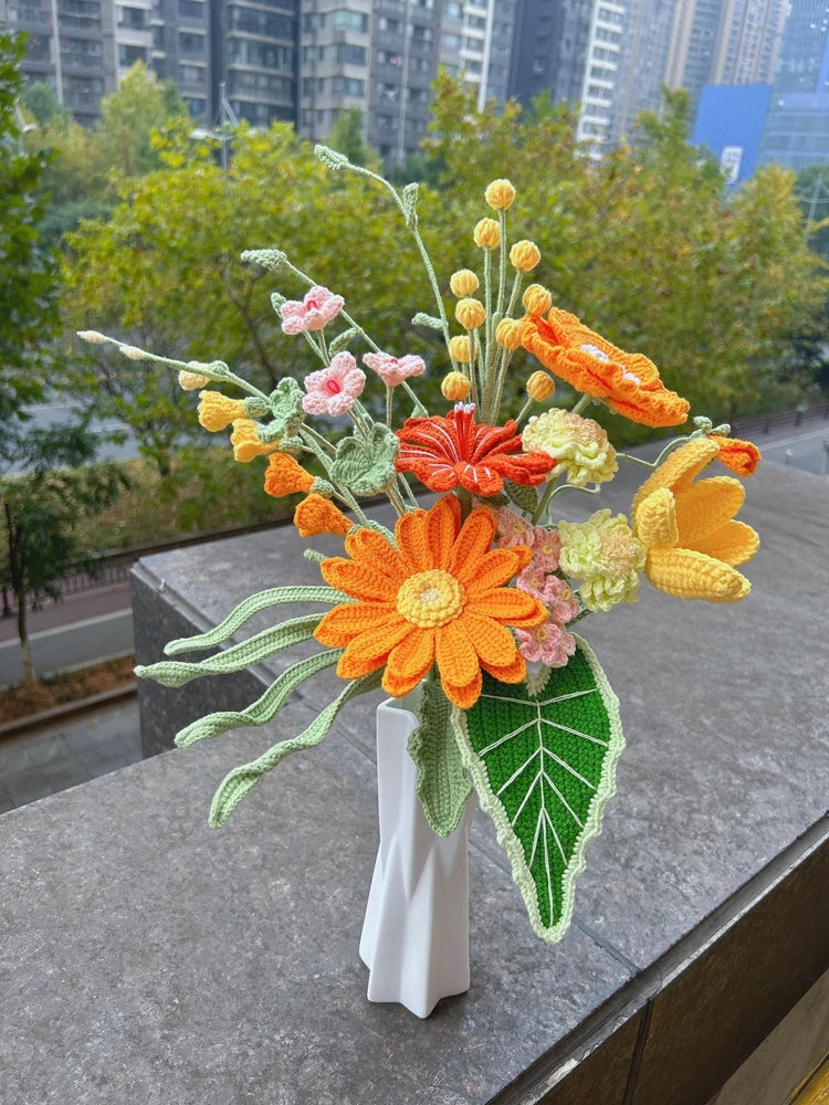 Handmade crochet flower bouquet featuring orange, yellow, and pink blooms on green stems
