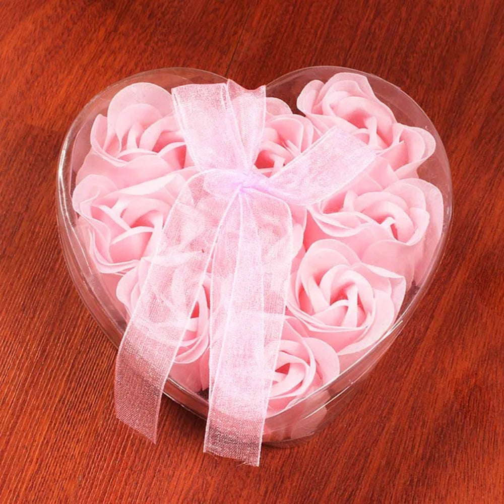 A heart-shaped clear plastic container filled with pink handcrafted soap roses tied with a sheer pink ribbon.