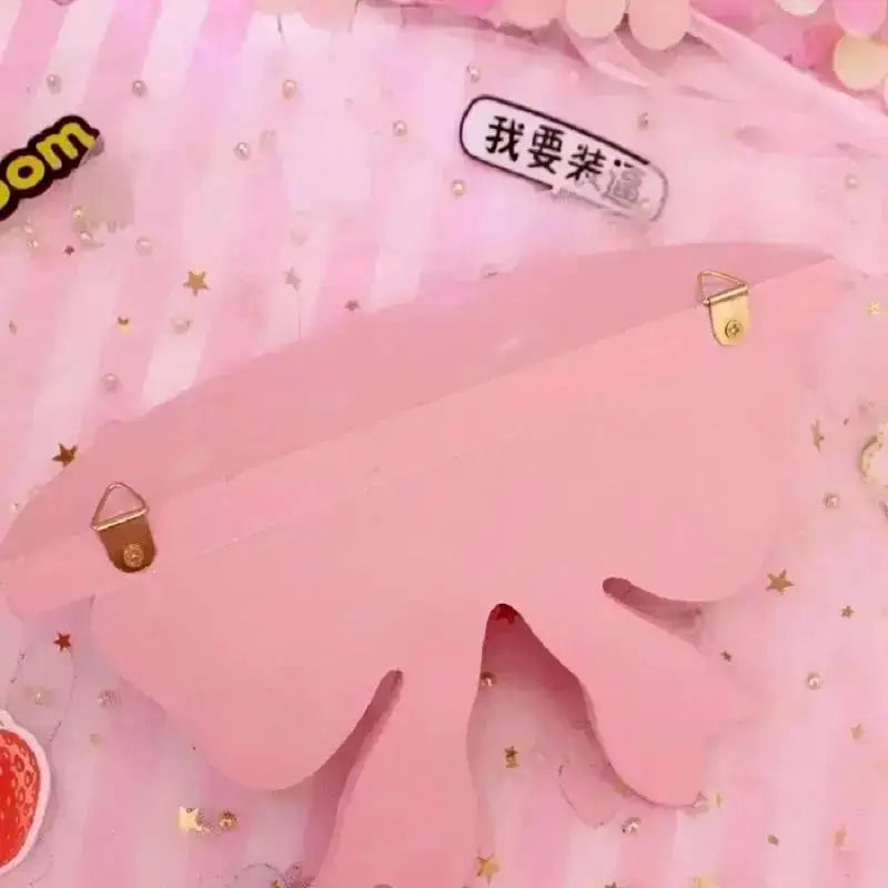 A pink decorative bow-shaped wooden wall shelf with gold accents and Chinese text.