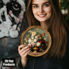 A young woman holds a round wooden sign featuring vintage floral wall art with roses and greenery.