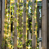 Vertical string lights with artificial green leaves draped on wooden slats for home decor