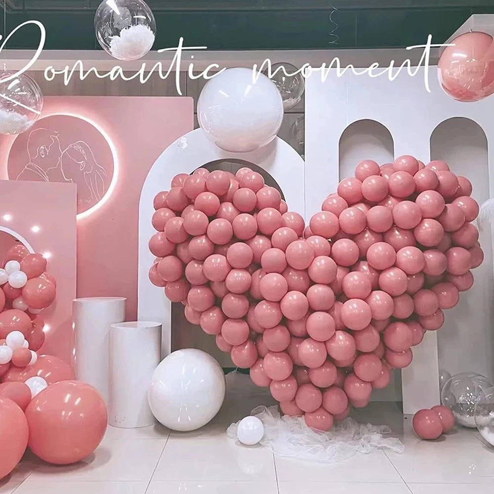 A heart shape made of pink latex balloons surrounded by white balloons and a light pink background.