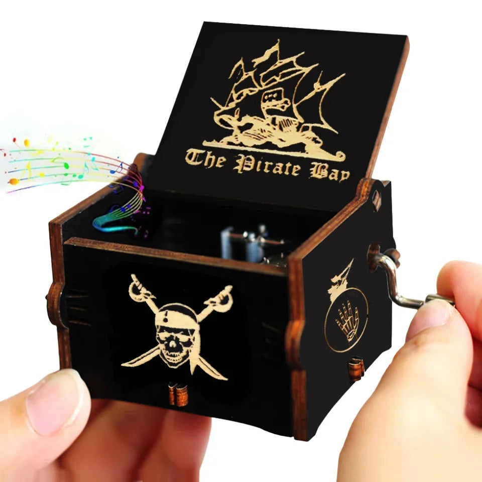 A carved wooden music box with a lid featuring a pirate theme and a small key.