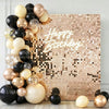 A gold and black balloon arrangement against a square wall backdrop with happy birthday text.
