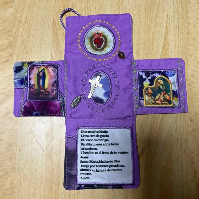 A handcrafted purple pocket shrine featuring a cross and religious imagery, embroidered with gold thread.