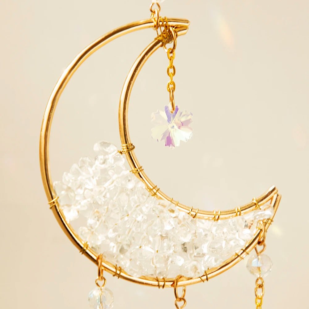 A gold moon-shaped crystal suncatcher with a dangling prism and clear crystals.