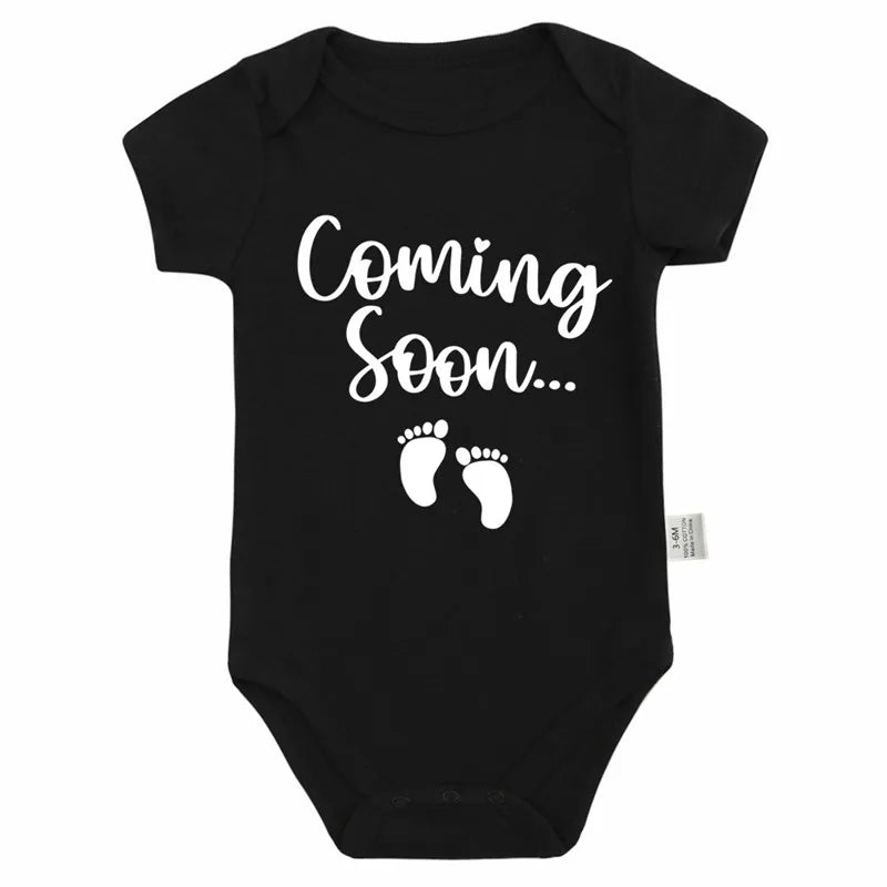 Black baby bodysuit with white text that reads Coming Soon