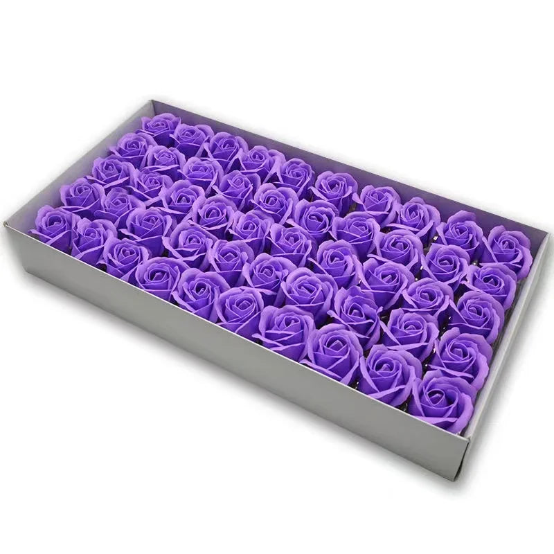 A rectangular box filled with purple artificial rose flower heads for DIY crafts and decor