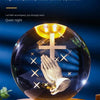 A clear glass crystal ball night light featuring a golden warm light illuminating a hand and a cross.